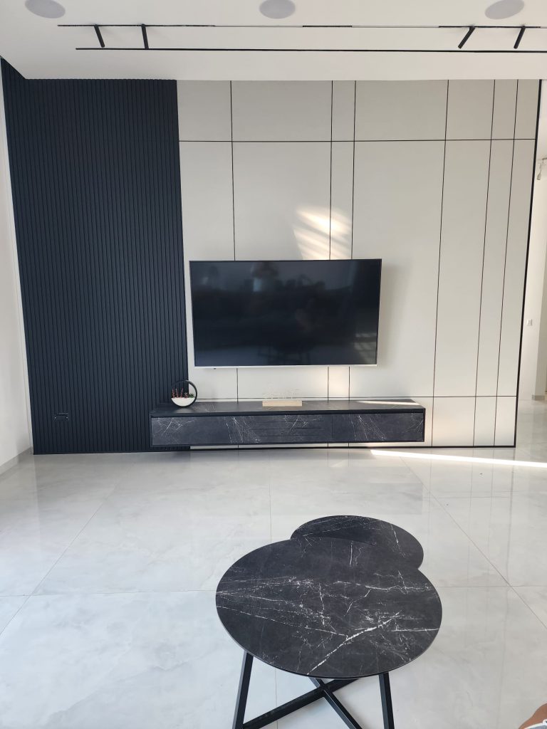 קיר TV בהיר עם פסי חלוקה כהים, אזור במראה סרגלים ומזנון תלוי בפרויקט משפחת גנסיה