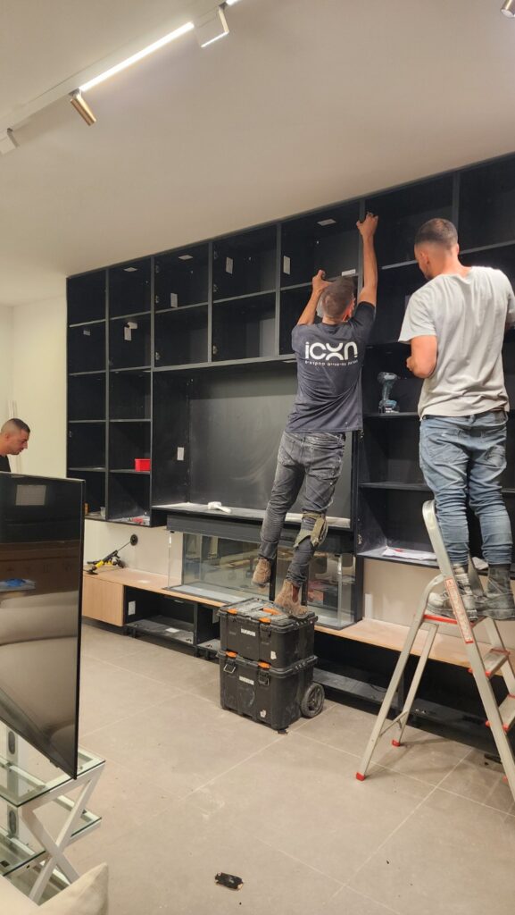 התקנת יחידות האחסון סביב המסך והקמין לפני הרכבת החזיתות בבית עדי הימלבלוי בהרצליה
